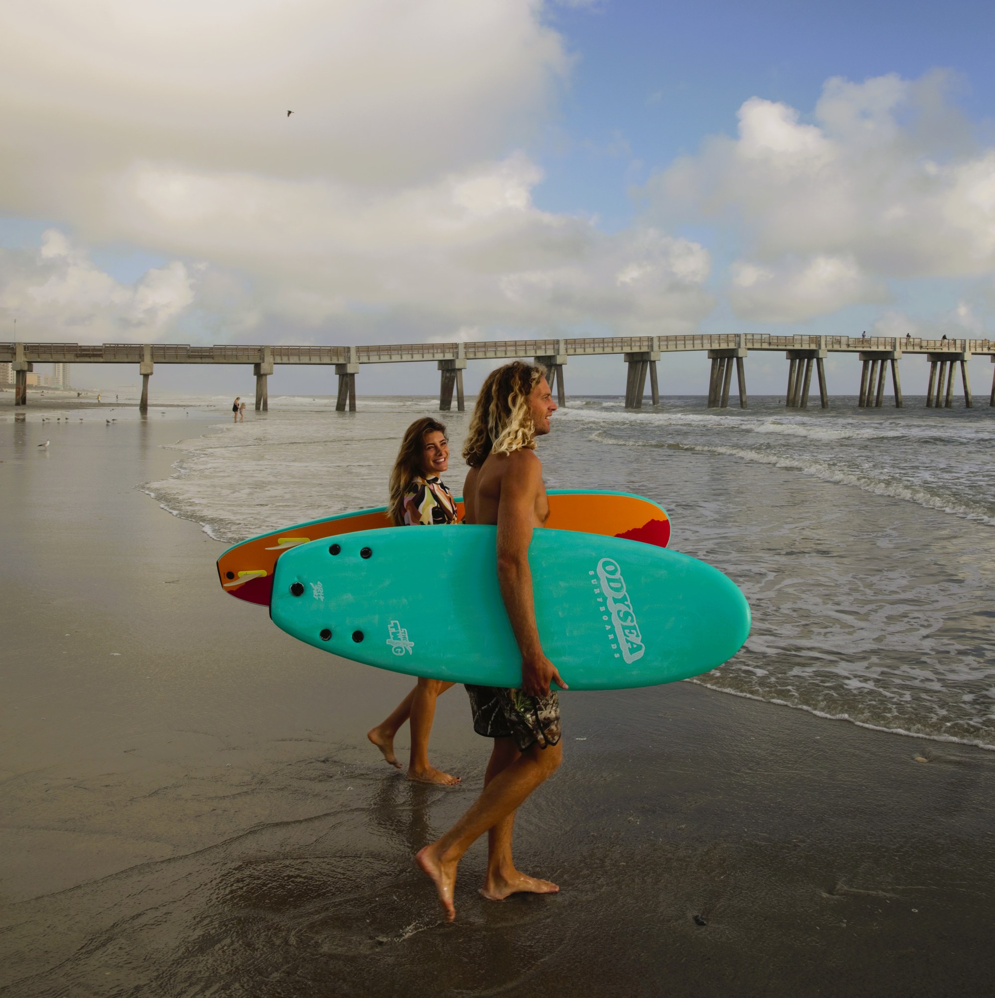 Blair and Bruna walking into the water at a Jacksonville pier.