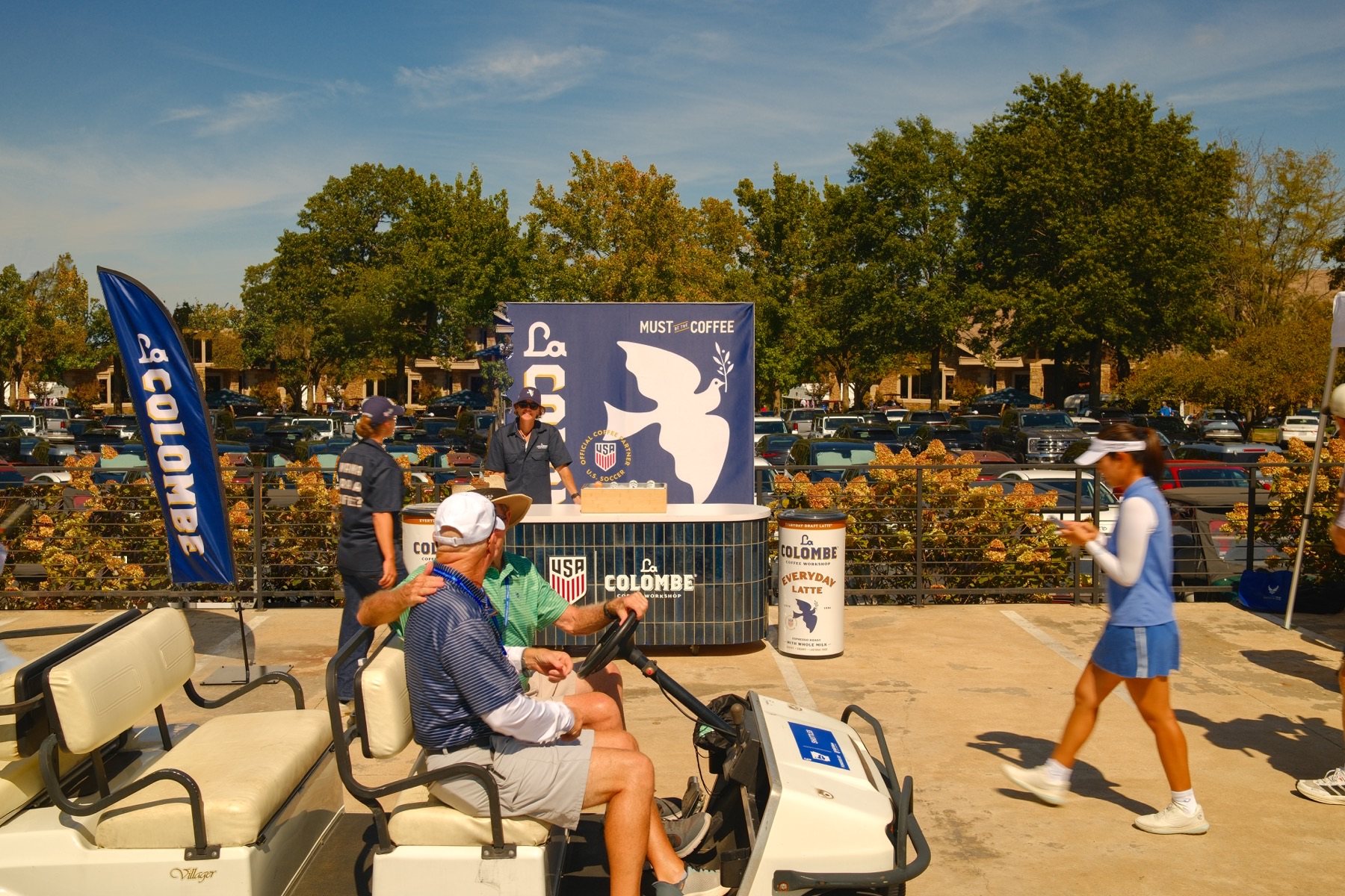 Full La Colombe sampling booth with feather flag and golf cart in foreground.